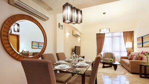 A modern hotel room with a dining area, a living room, and a large round mirror. - Village Residence Clarke Quay (Singapore)