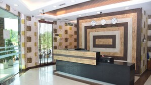 A reception desk with a modern design, a glass partition, and a view of greenery outside. - Sky Star Hotel at KLIA KLIA2 (Sepang)