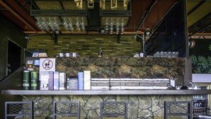 A bar area with a stone wall, bar stools, and various bottles and glasses on the counter. - Sky Star Hotel at KLIA KLIA2 (Sepang)