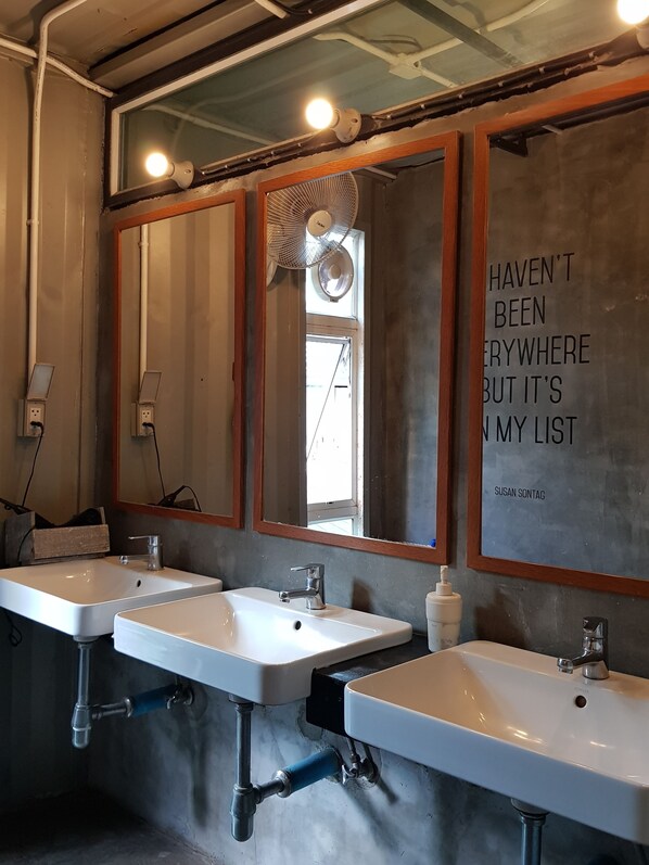 A modern bathroom with two sinks, a mirror, and a motivational quote on the wall.