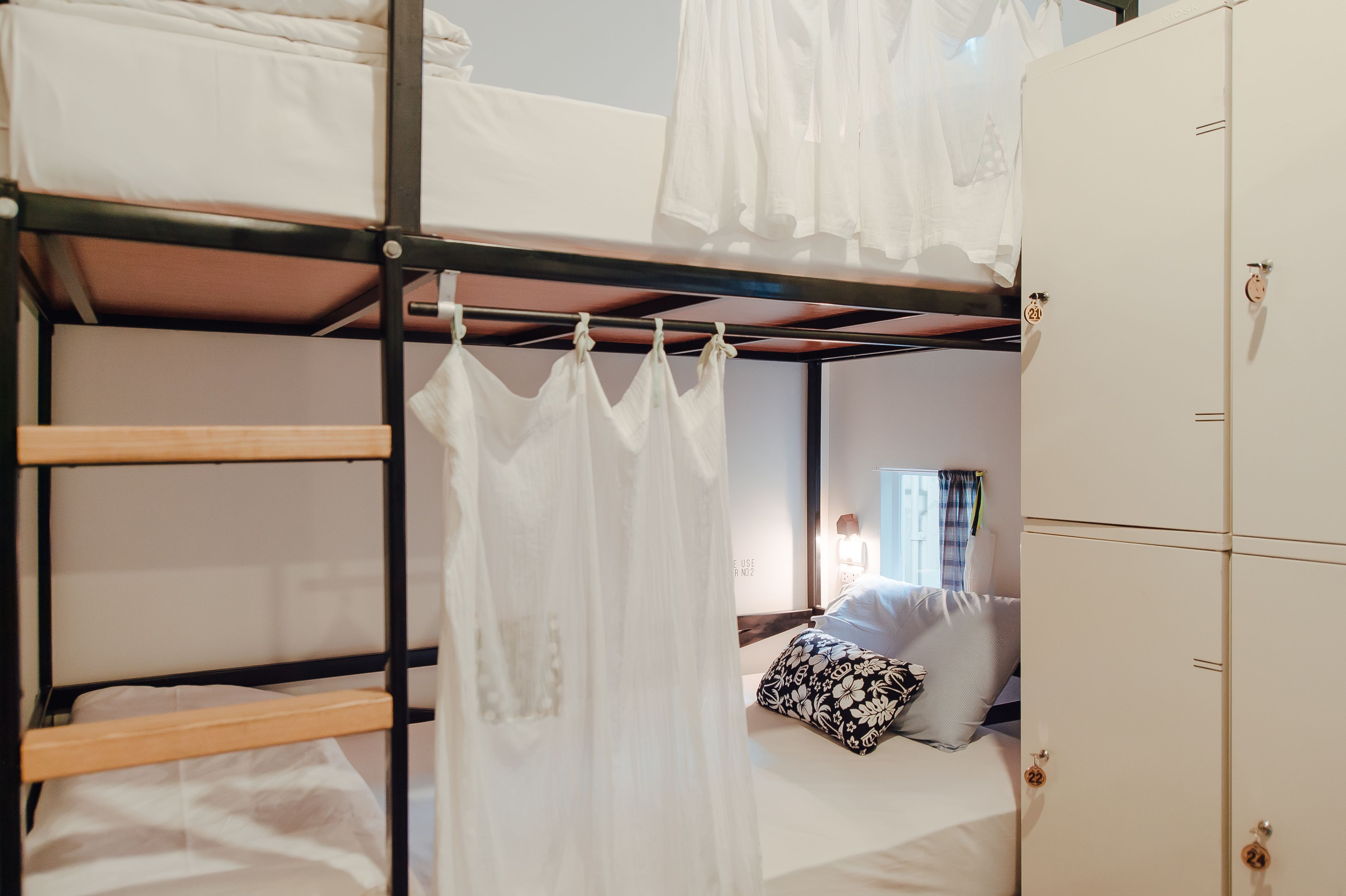 Una cama litera con dosel, una cama individual con almohada floral y un armario con cerradura.