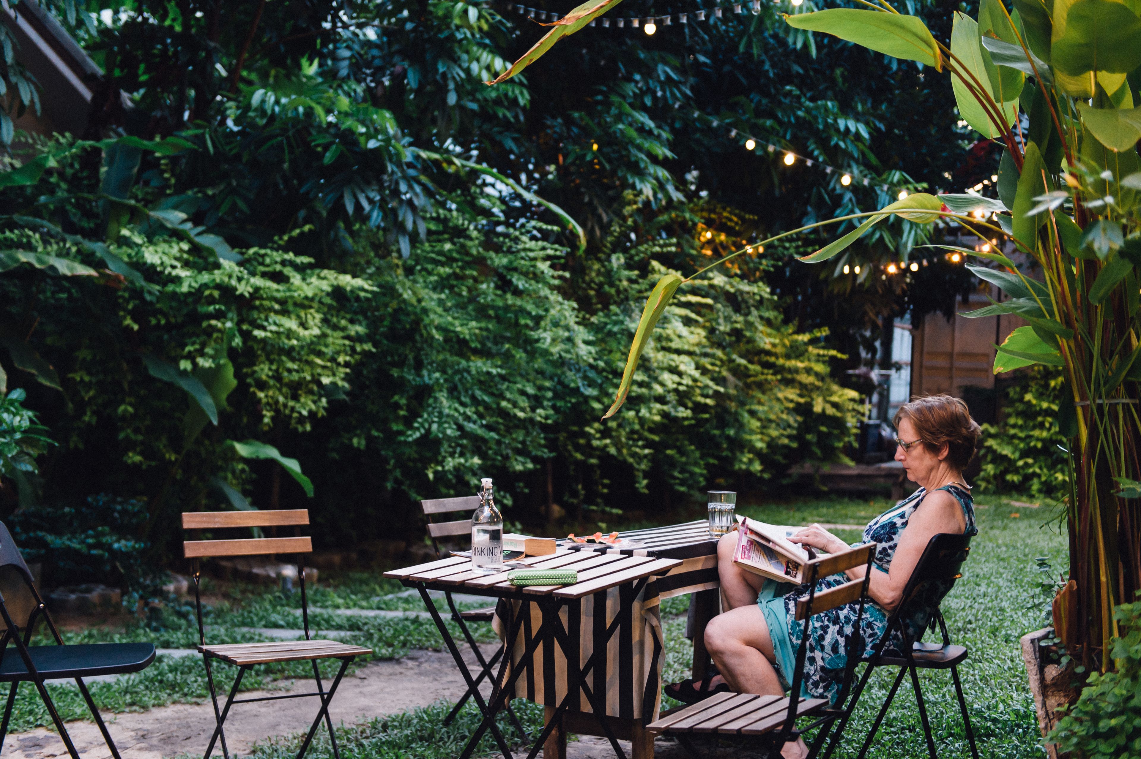 Un espacio al aire libre con mesa y sillas de madera, rodeado de abundante vegetación.