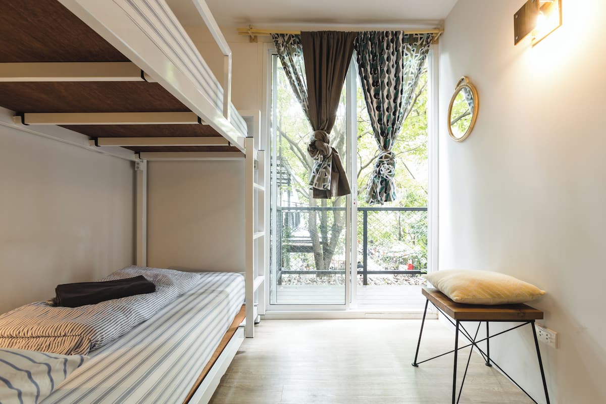 A compact room with a bed, a small table, and a window with curtains.
