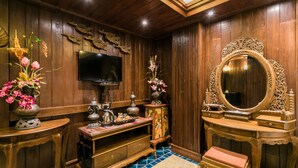 Une chambre traditionnelle avec des boiseries, un téléviseur, un miroir décoratif et un petit banc.