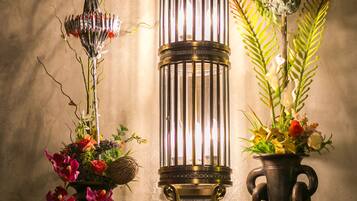 A wall-mounted lantern with a candle holder and two vases with flowers.