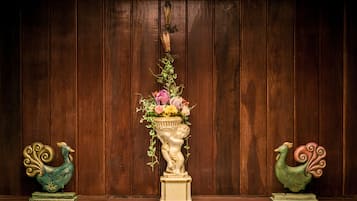 A wooden wall with two decorative peacock figures on either side of a central floral arrangement in a vase.