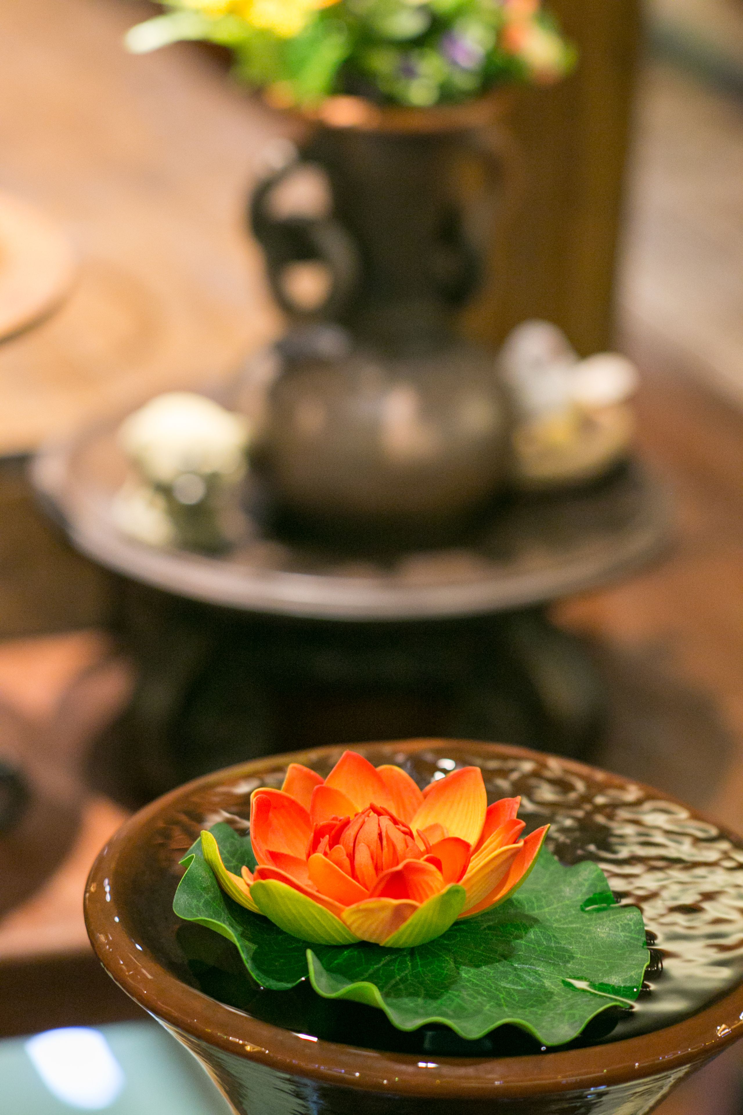 A close-up of a lotus flower in a ceramic bowl with a decorative background.
