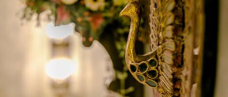 A close-up of a bicycle wheel with a decorative handlebar and a floral arrangement in the background.