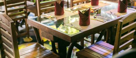 Un espace repas avec des chaises et des tables en bois, certaines ayant des serviettes pliées posées dessus.