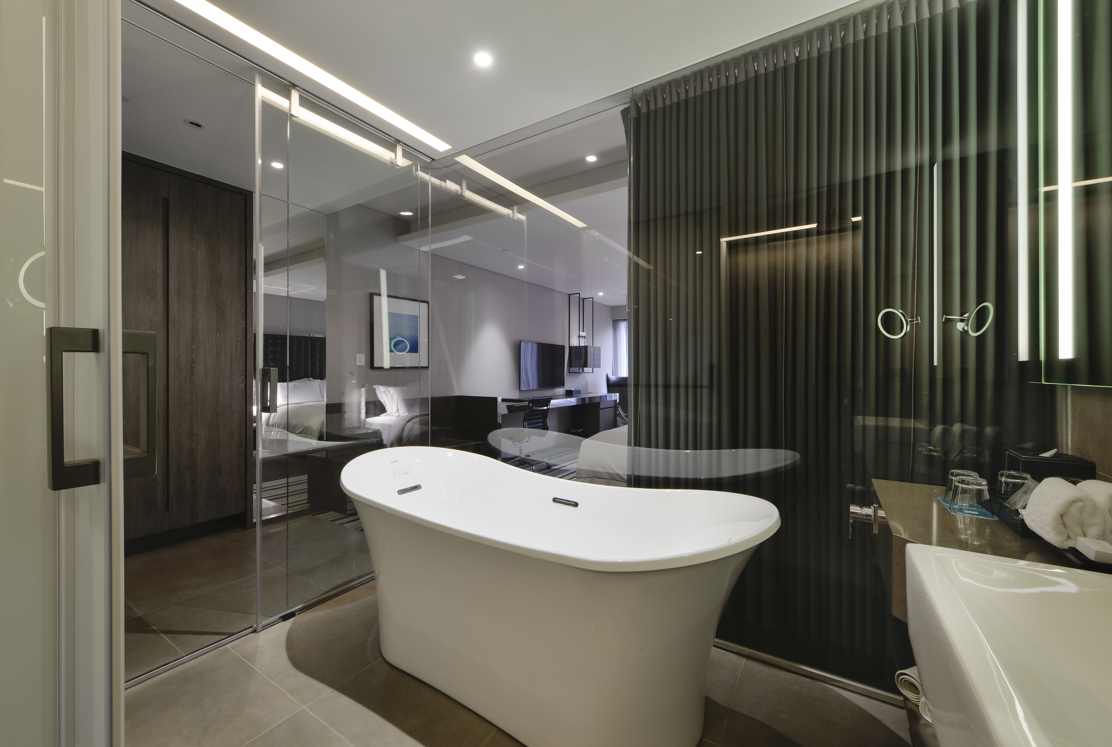 Un baño moderno con una bañera independiente, cabina de ducha con mampara de vidrio y un tocador con espejo.
