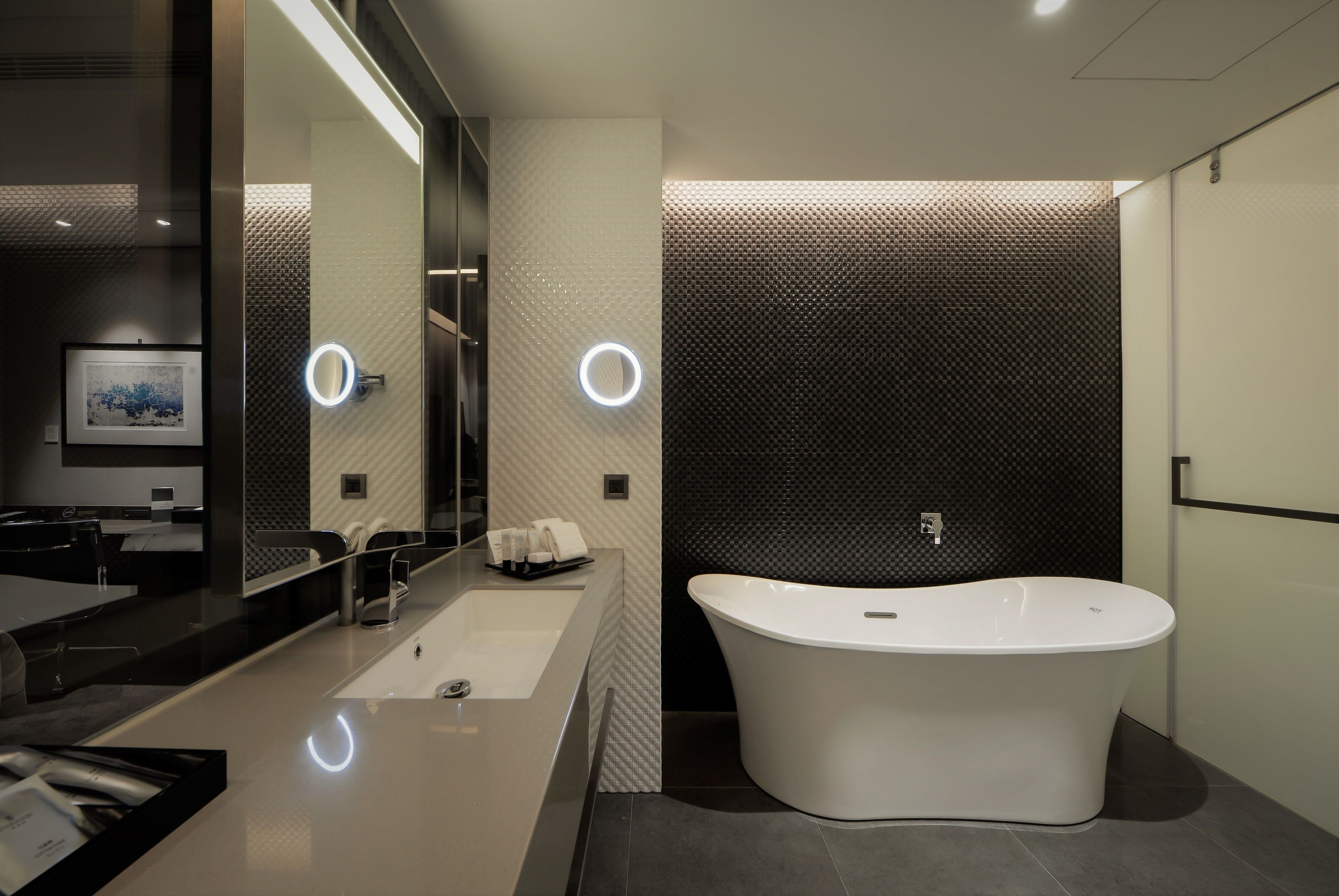 A modern bathroom with a freestanding bathtub, a large mirror, and a vanity with a sink.