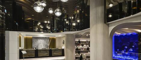 A modern lobby with a reception desk, seating area, and a large aquarium.