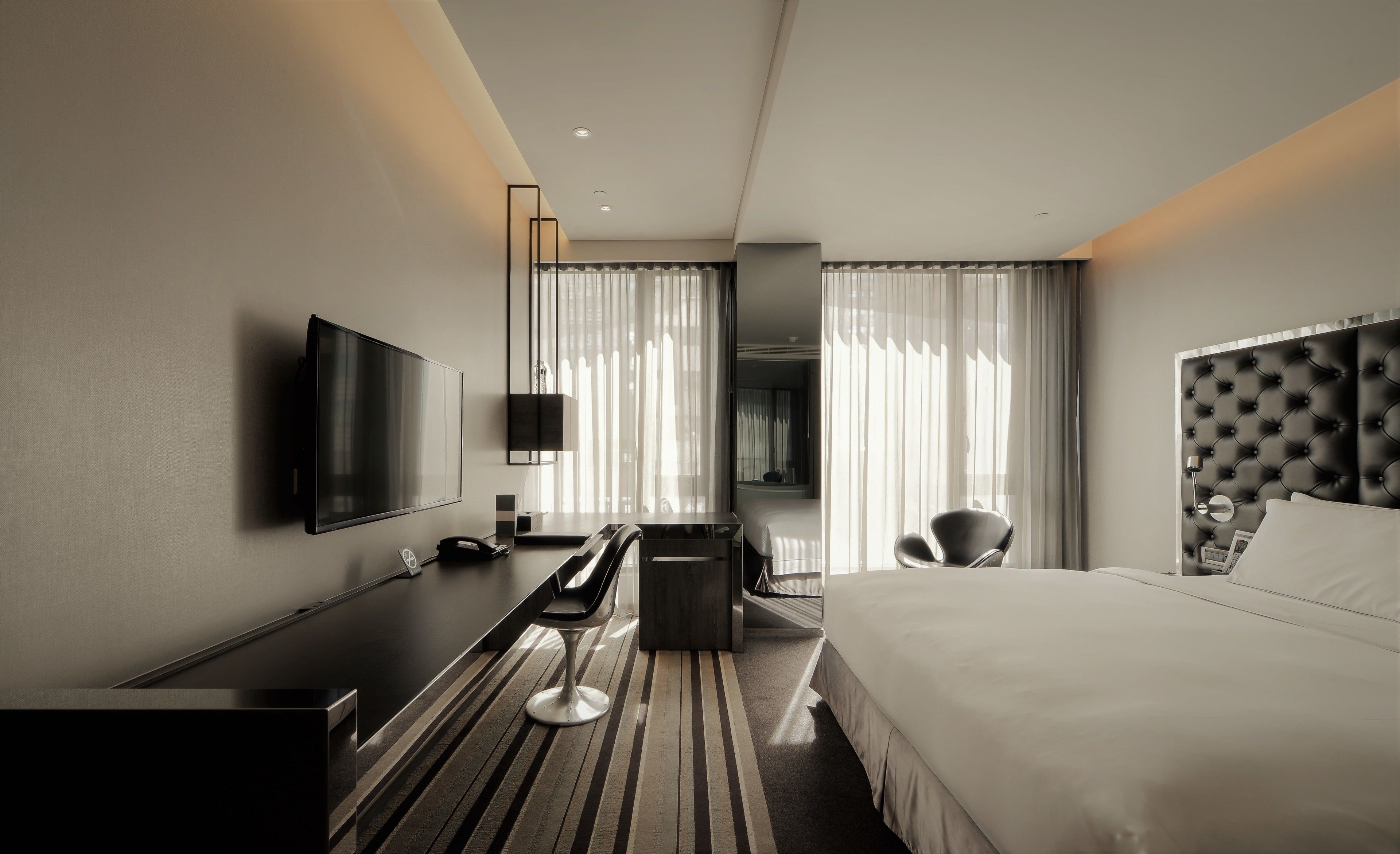 Una habitación de hotel moderna con una cama grande, un televisor de pantalla plana, un escritorio y una silla.