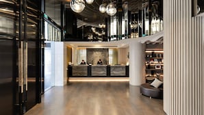 Un lobby moderno con una recepción, zona de estar y un diseño de techo único.