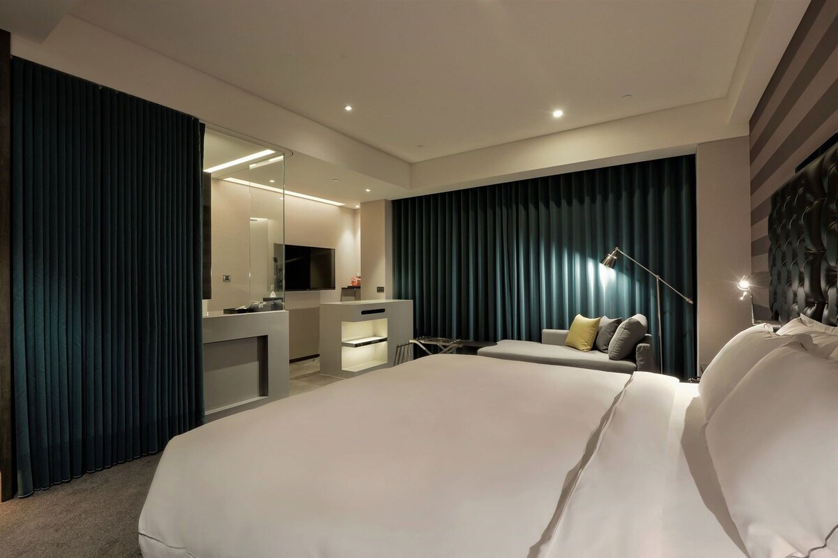 Una habitación de hotel moderna con una cama grande, un escritorio, una silla y un televisor.