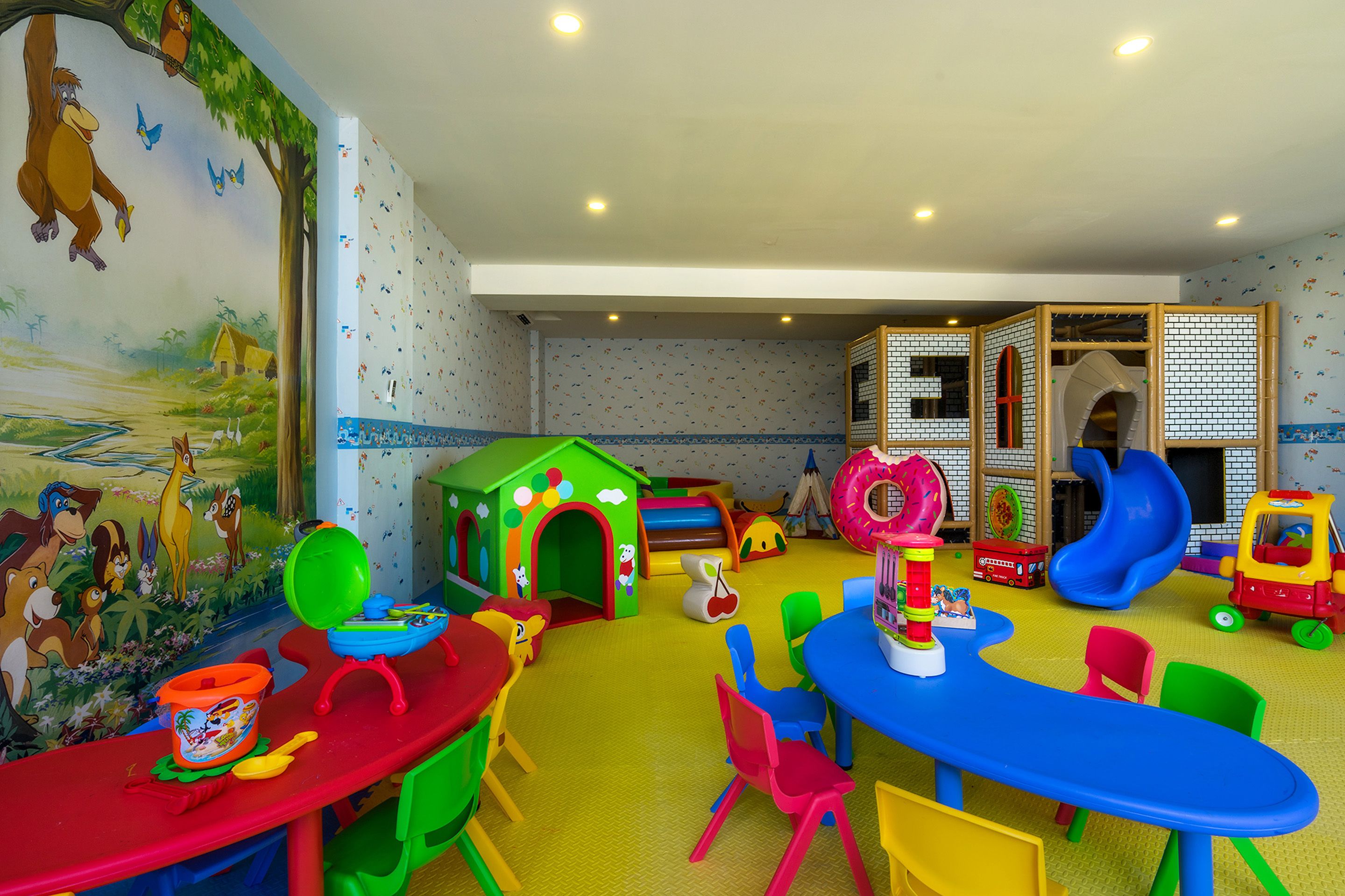 Una sala de juegos para niños con un tobogán, una casita de juegos y distintos juguetes.