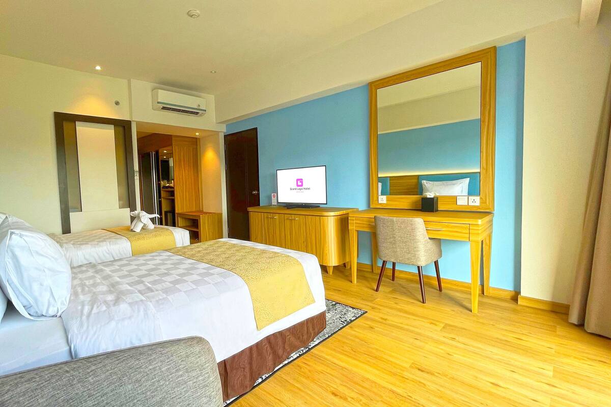 A hotel room with a bed, a desk, a chair, a television, and a large mirror.