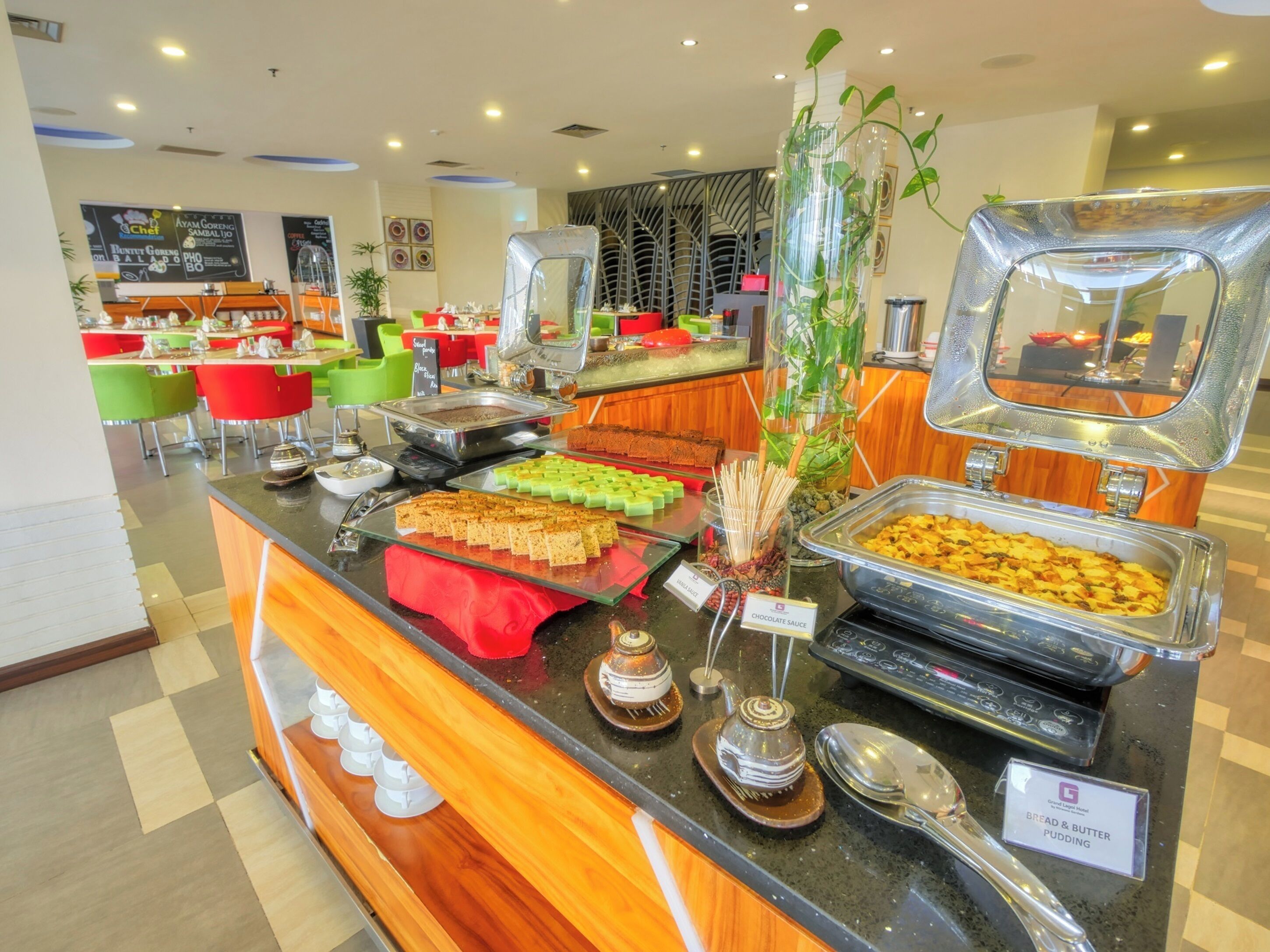 A buffet counter with various food items and a sign indicating bread & butter pudding.
