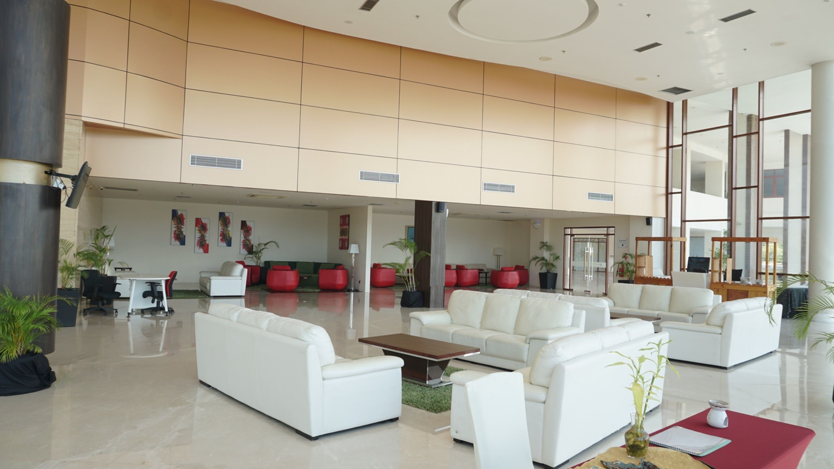 A spacious lobby with white sofas, red chairs, and a coffee table.