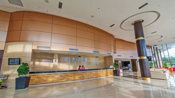 A modern hotel lobby with a reception desk, a large column, and a seating area.