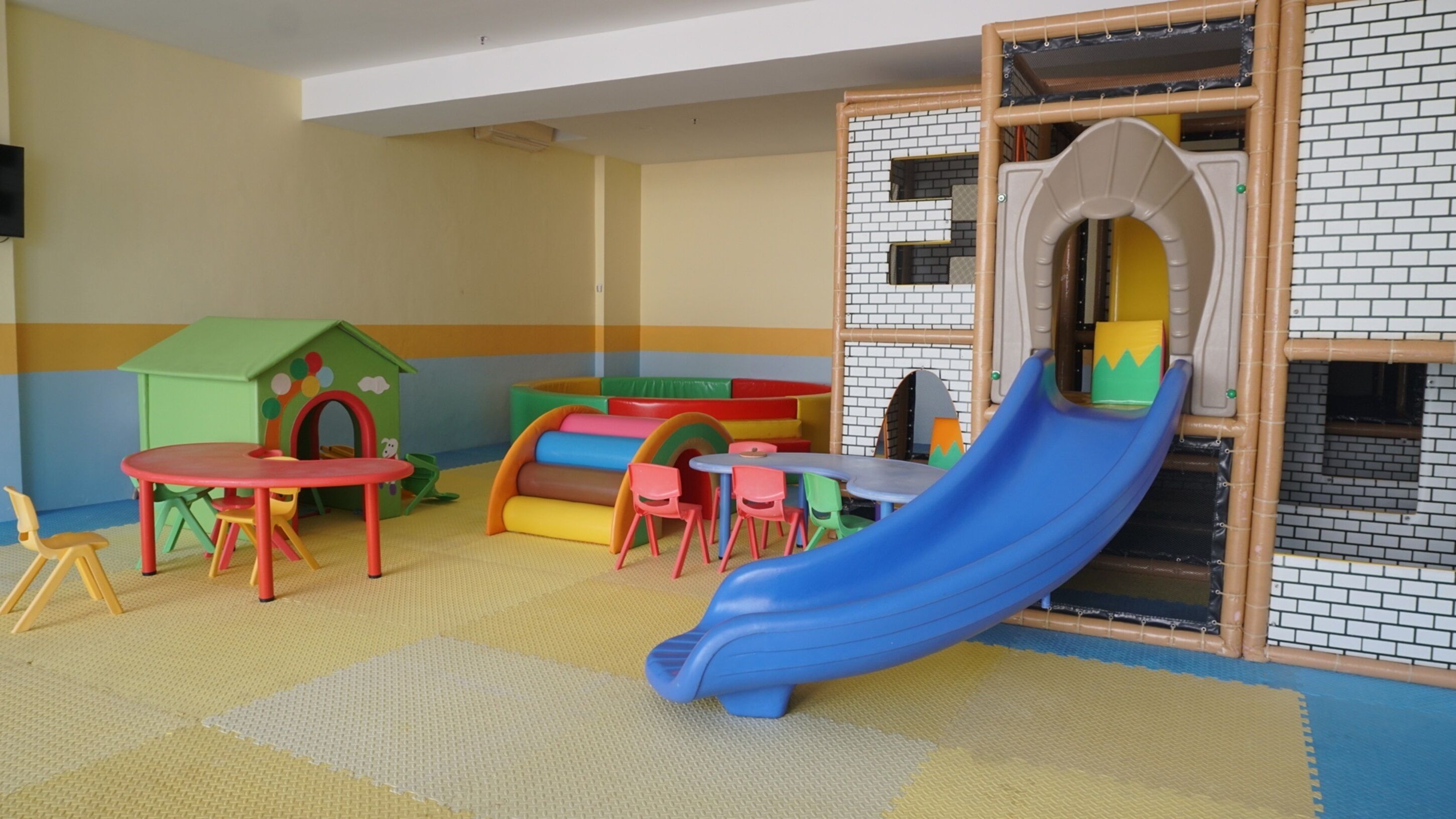 Ein Spielbereich für Kinder mit Rutsche, Spielhaus und Sitzgelegenheiten.