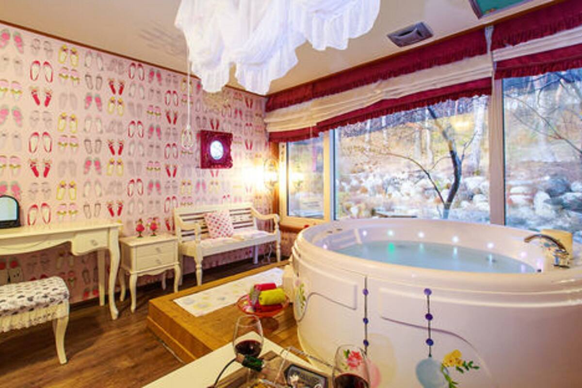A cozy room with a large bathtub, a desk, and a chair.