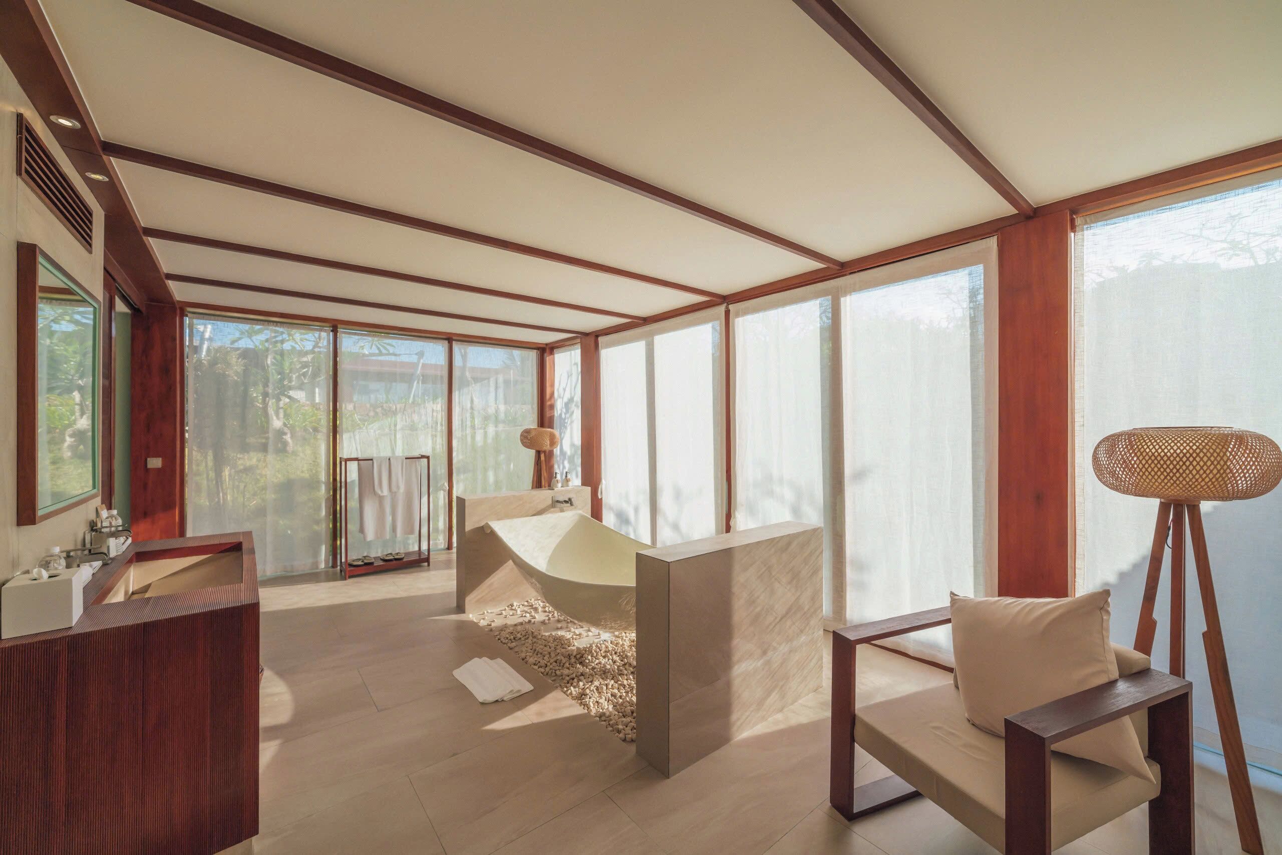 A modern bathroom with a freestanding bathtub, a wooden vanity, and a large window providing natural light.