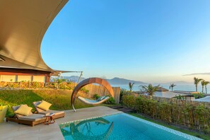 A poolside area with a curved roof, a hanging chair, and a view of the sea. - Fusion Resort Cam Ranh (Cam Lam)