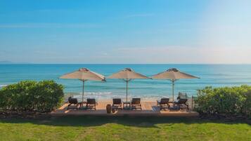 A poolside area with lounge chairs and umbrellas overlooking the ocean.