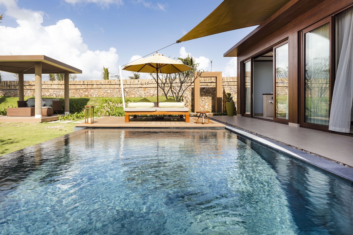 Ein Swimmingpool mit Liegestuhl und einer Pergola.