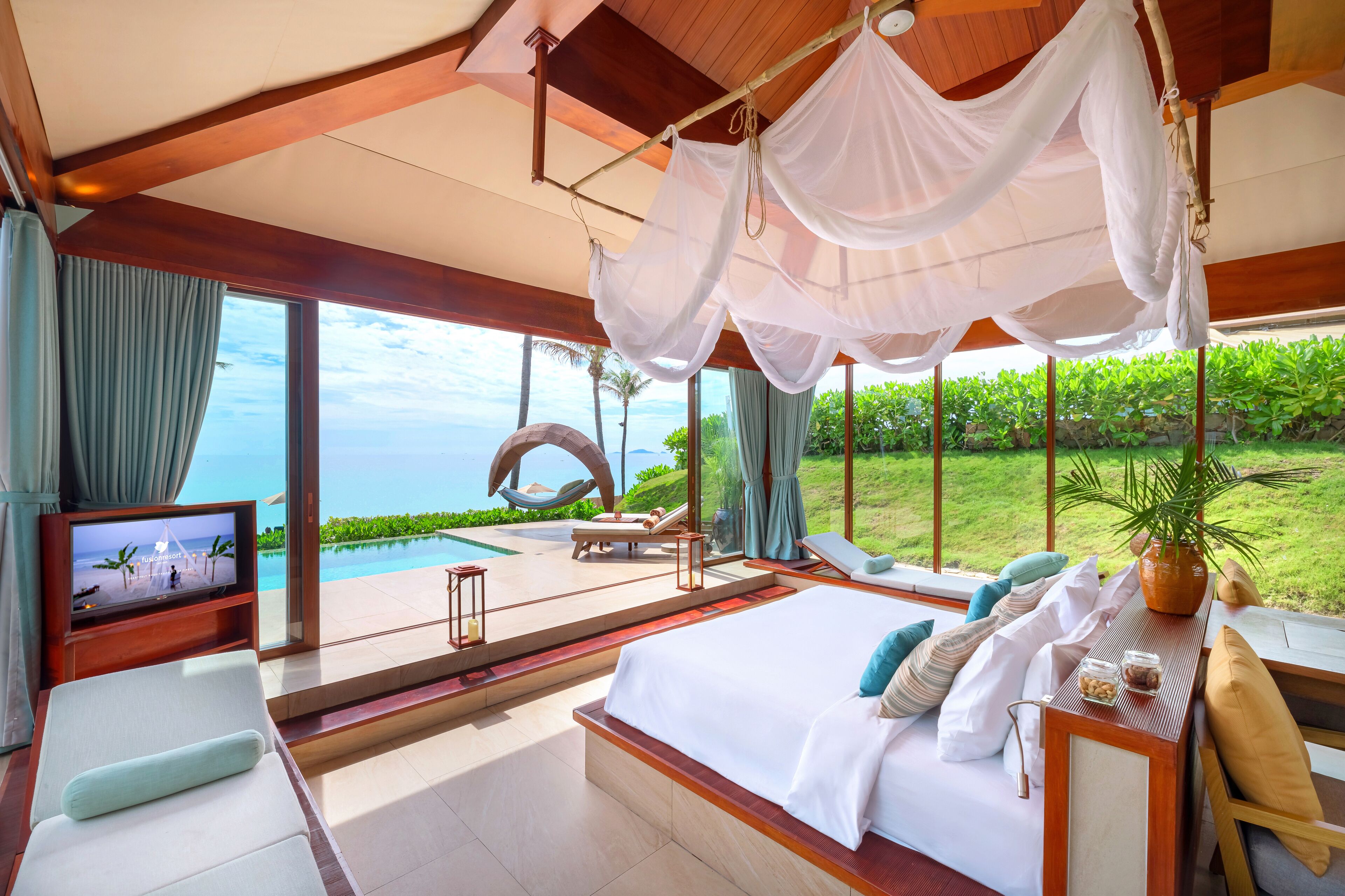 A luxurious bedroom with a large bed, a TV, and a view of the ocean.