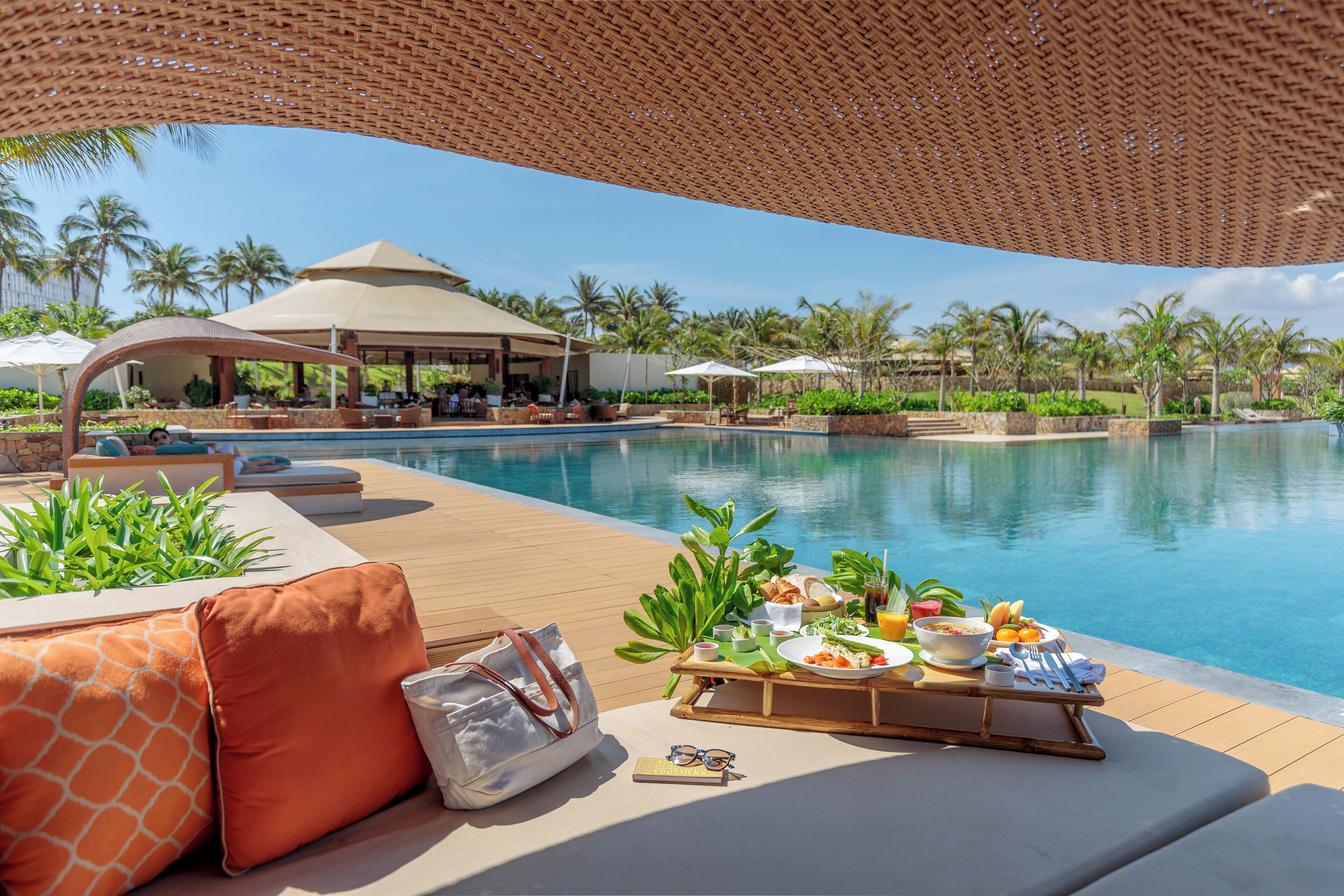 A poolside setting with a dining table, lounge chairs, and a covered area.