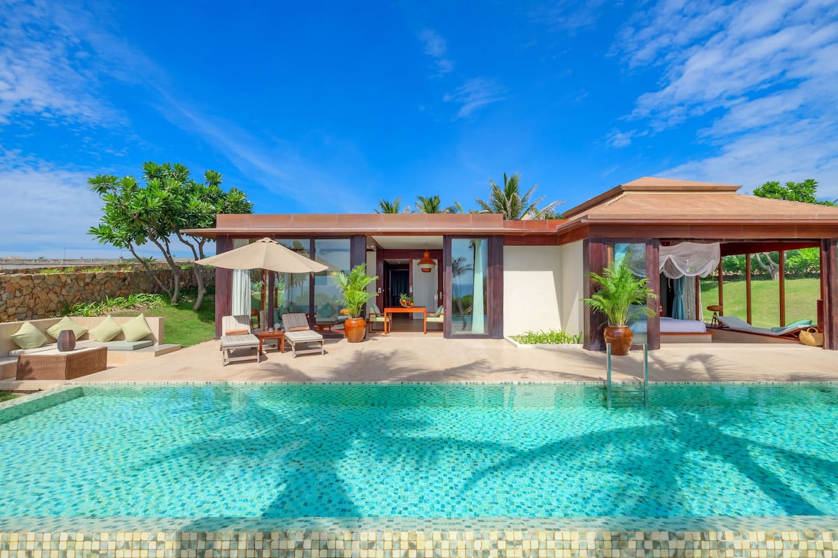 Ein modernes Haus mit Schwimmbad, Sitzgelegenheit im Freien und Garten.