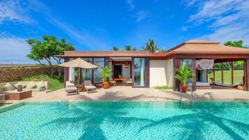 A modern house with a swimming pool, outdoor seating, and a garden.