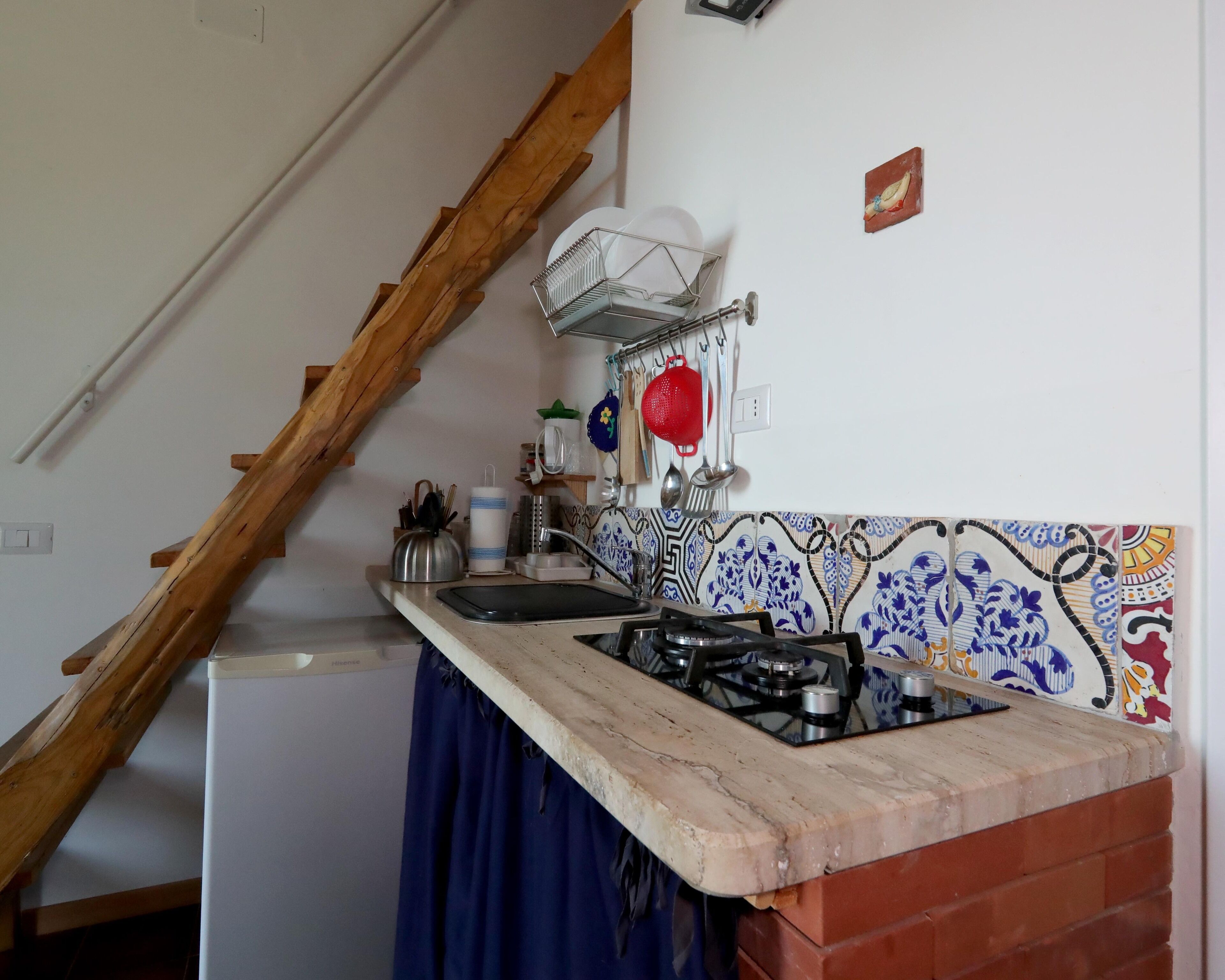 Eine Küche mit Gaskochfeld, Spüle und einer Holztreppe.