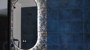 Un baño con un espejo redondo, azulejos azules y un estampado floral en la pared.