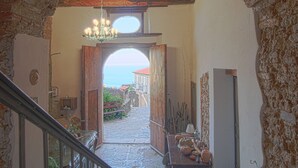 A stone staircase leading to a room with a view of the sea, a wooden table with pottery, and a chandelier. - La Casa sul Blu Albergo Diffuso (Pisciotta)