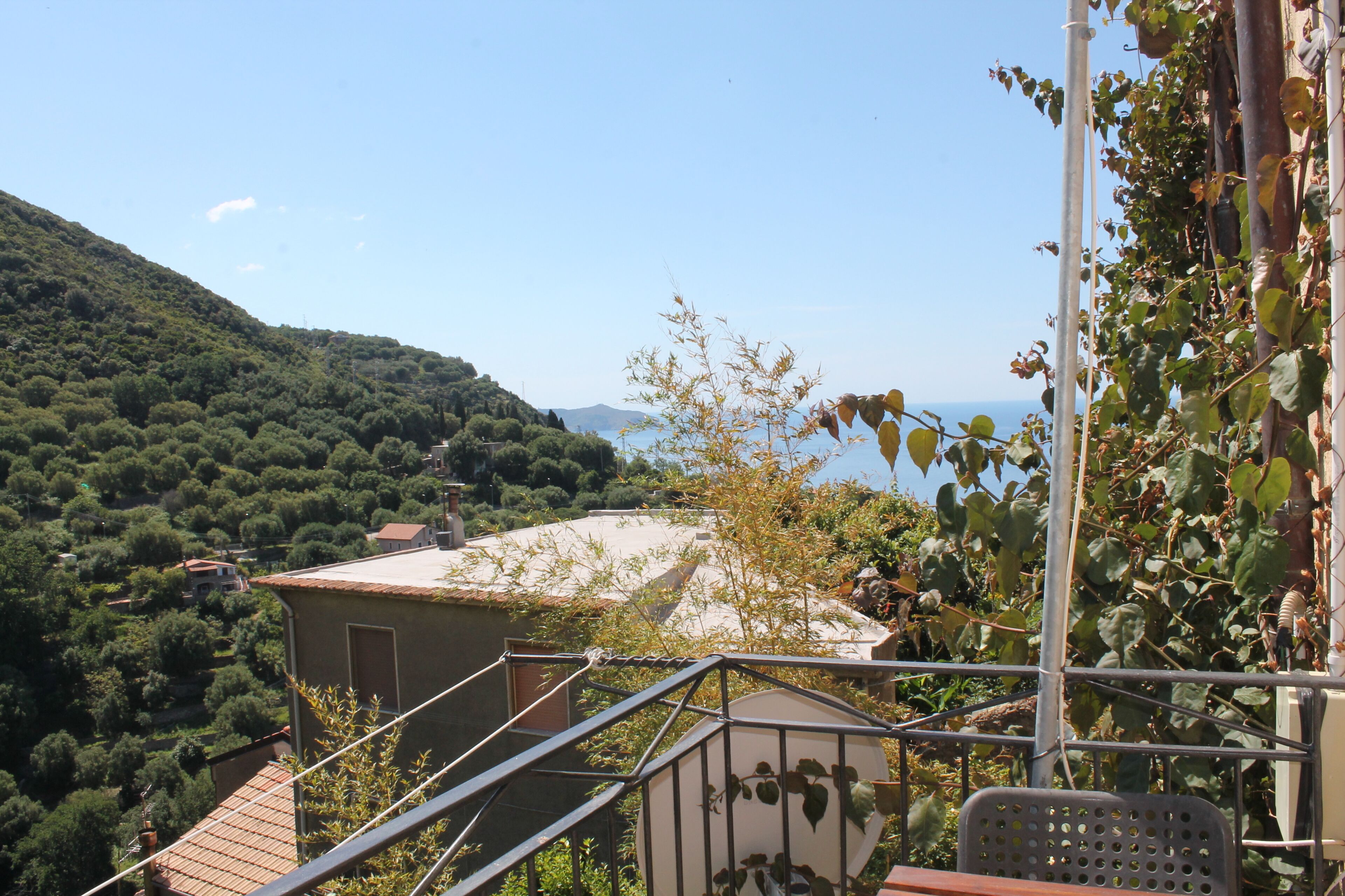 A balcony with a view of a hillside and a body of water.