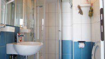 A bathroom with a shower, two toilets, a sink, and a mirror.