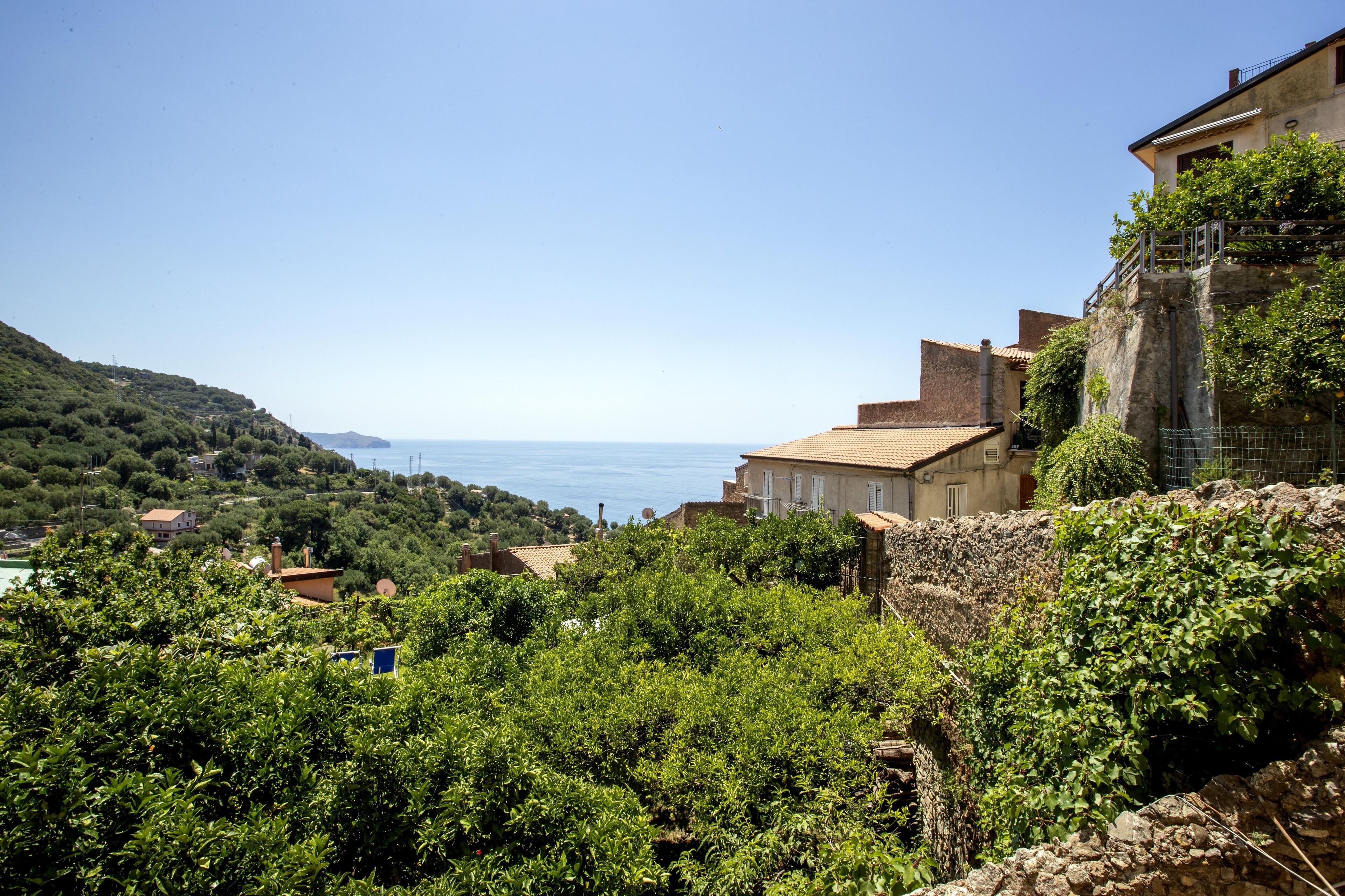 A coastal village with terraced houses, lush greenery, and a view of the sea.