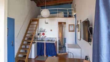 Une cuisine compacte avec un escalier en bois, un coin repas avec une table et des chaises, et une porte bleue.