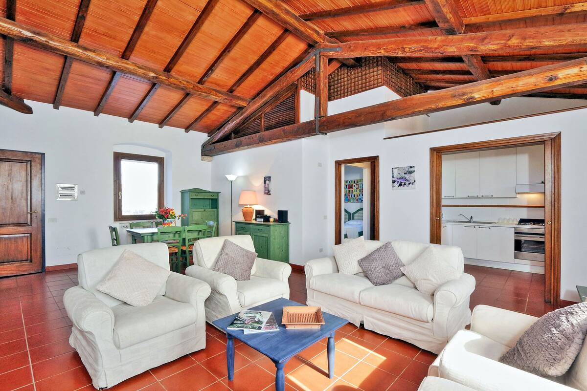 Un vaste espace de vie comprenant deux canapés blancs, une table basse et un plafond en bois.