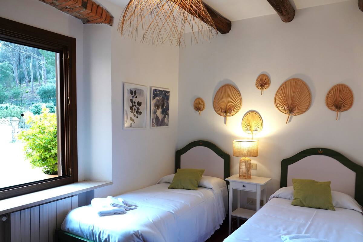 Une chambre avec deux lits, une fenêtre et des œuvres d’art murales.