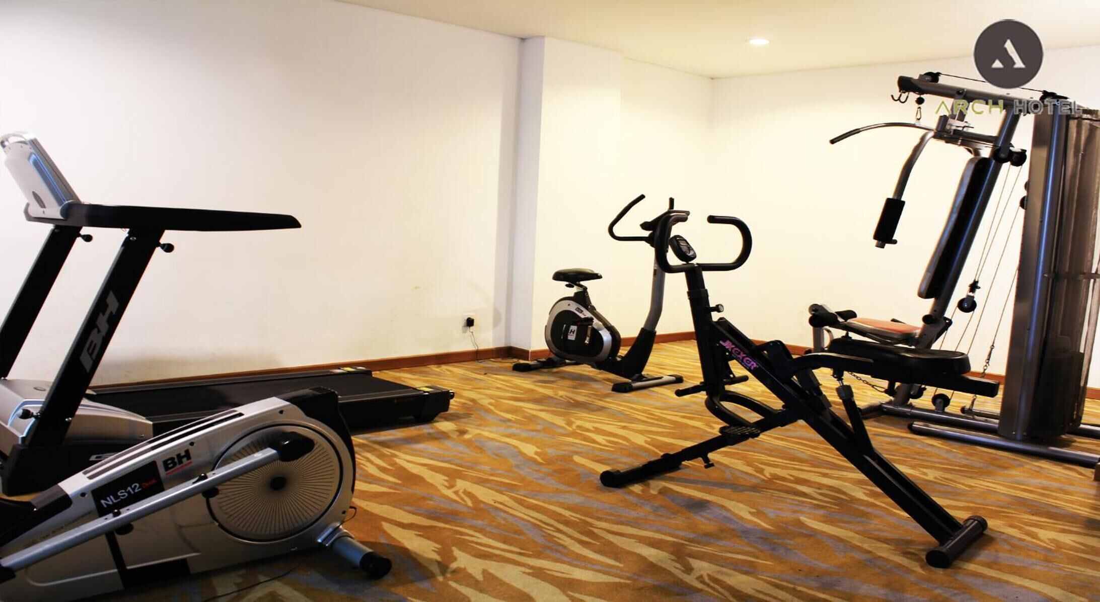 Un gimnasio de hotel con bicicletas estáticas, una elíptica y una máquina de pesas.