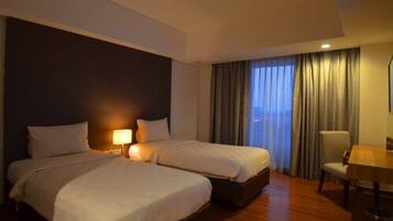 A hotel room with two beds, a desk, and a chair.