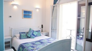 A bedroom with a bed, bedside tables, a nightstand, a window with curtains, and a view of the outside. - Hotel Le Relais Des Deux Vallees (Salvagnac)