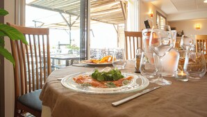 A dining table set with a plate of food, wine glasses, and a candle. - Hotel Le Relais Des Deux Vallees (Salvagnac)