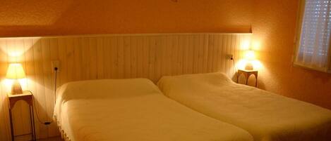 Una habitación con dos camas, un cabecero de madera y dos lámparas de noche.