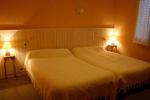 A room with two beds, a wooden headboard, and two bedside lamps.