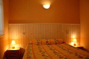 A bedroom with a wooden headboard, two bedside tables with lamps, and a floral bedspread.